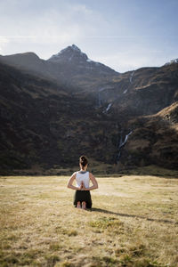 Woman performing yoga poses in alpine mountain landscape, gastein, austria