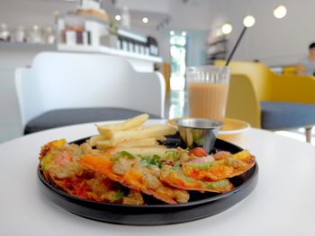 Close-up of pizza and french fries on table at cafe