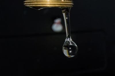 Close-up of water drop hanging from glass
