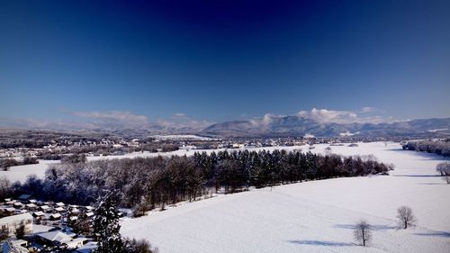 Snow covered landscape against blue sky