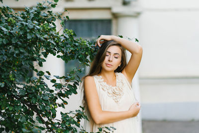 A romantic young woman in a summer dress has closed her eyes and is enjoying a summer day standing