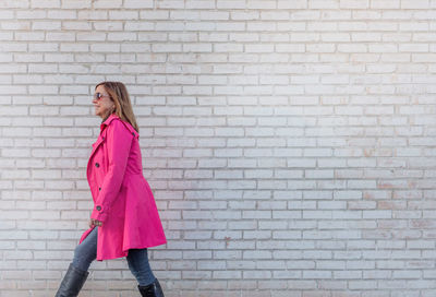 Side view of woman walking by brick wall