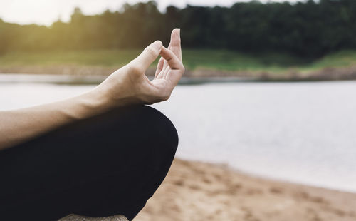 Midsection of person hand on water at beach