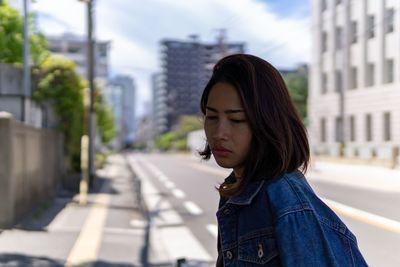 Woman looking down against buildings in city