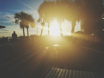 Silhouette man and palm trees against sky during sunset