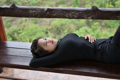 High angle view of thoughtful young woman lying down on bench