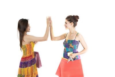 Friends giving high-five while standing against white background