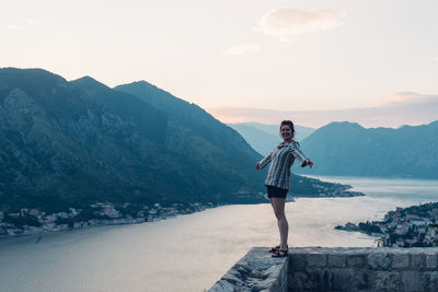 Portrait of woman standing in retaining wall against river