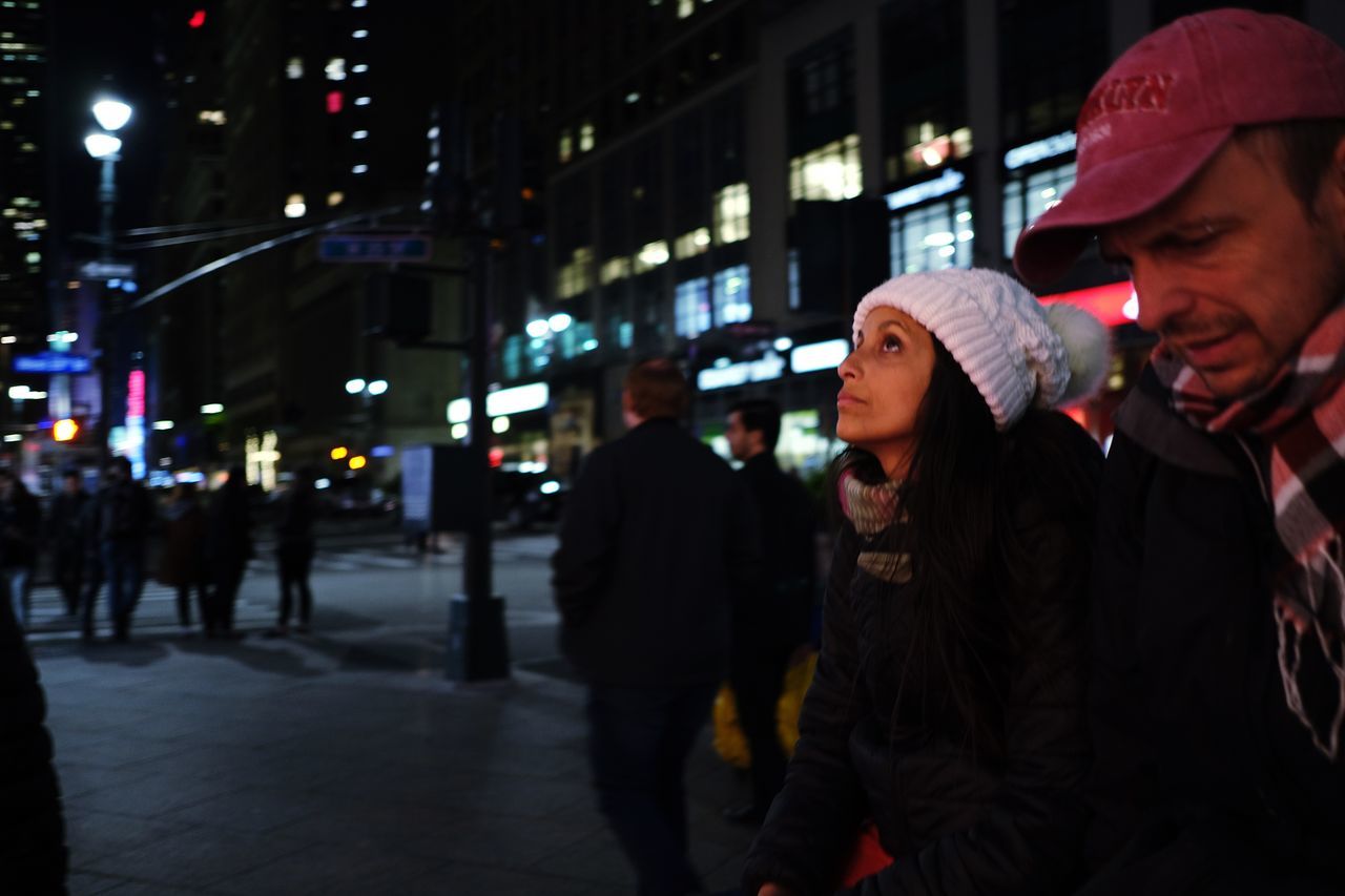 night, city, illuminated, architecture, lifestyles, street, real people, leisure activity, men, incidental people, building exterior, city life, people, young adult, group of people, clothing, built structure, adult, hat, young men, outdoors, warm clothing, nightlife