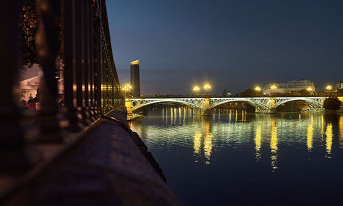 Illuminated bridge over river at night