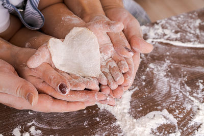 Family in kitchen, close-up palm from above lies a heart-shaped dough