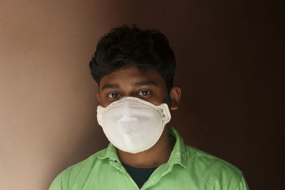 Portrait of young man with mask against wall