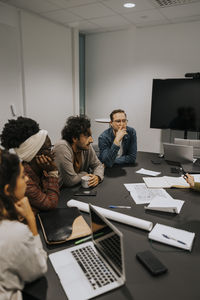 Multiracial colleagues sitting at conference table in board room