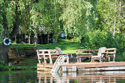 Chairs and table by swimming pool against trees in park