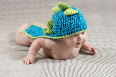 Full length of cute baby girl wearing knit hat while lying down on bed