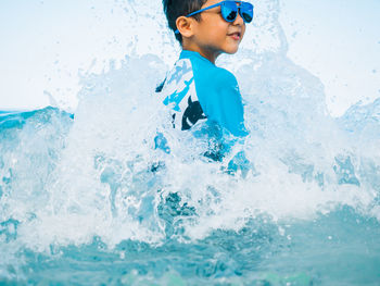 Full length of boy splashing water in sea