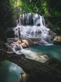 Solo traveler enjoy scenic waterfall, turquoise pond in forest. erawan fall, kanchanaburi, thailand.