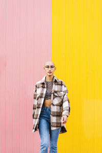 Confident young woman walking in front of wall