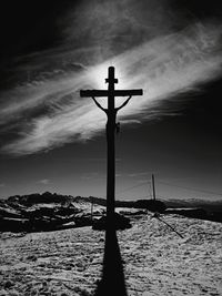 Cross on land against sky