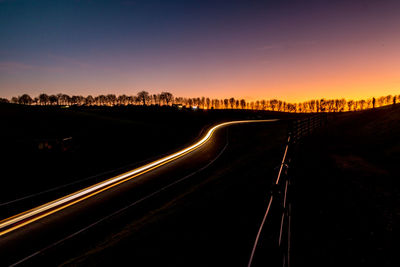 Light trails on road against sky at night