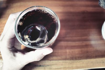 Close-up of hand holding drink on table