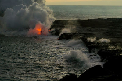 Lava on rocky shore with smoke at kilauea in hawaii