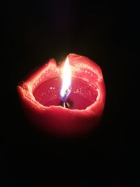 Close-up of burning candle against black background