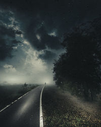 Empty road amidst trees against sky