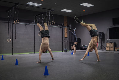 Athletes walking on hand while exercising at gym