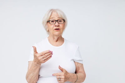 Portrait of smiling woman gesturing against white background