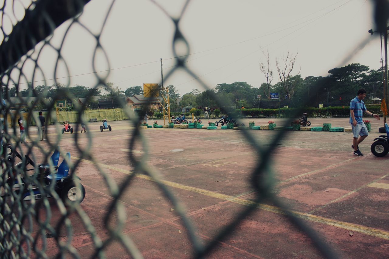 PEOPLE RIDING BICYCLES ON CHAINLINK FENCE