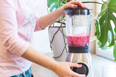 Midsection of woman holding drink at home