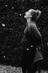 Happy pregnant woman enjoying snow at yard