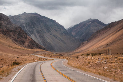 Scenic view of road by mountains against sky