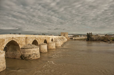 Arch bridge over river against sky