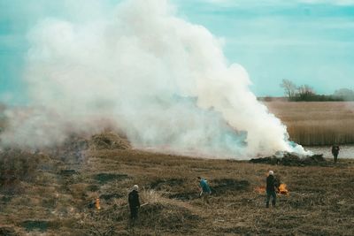 Smoke emitting from volcanic on field against sky