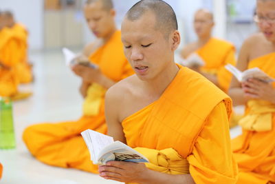 Close-up of monks reading books while sitting in temple