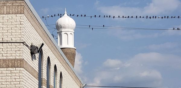 Low angle view of cross amidst buildings against sky