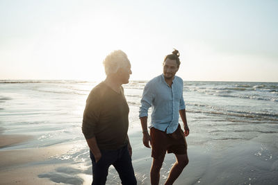 Father and son walking by seashore at beach