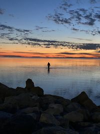 Scenic view of rocks on beach against sky during sunset