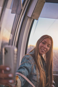 Young tourist sitting on the cableway in caracas enjoying a photo taken on her smartphone. 