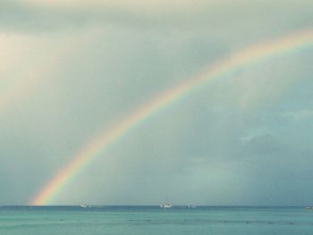 Scenic view of rainbow over sea against sky