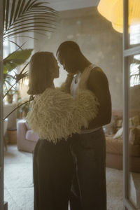 Romantic young woman standing with boyfriend at home