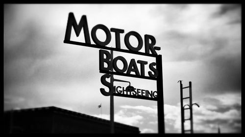 Low angle view of sign board against cloudy sky