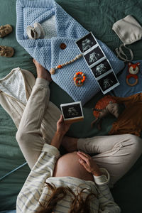 Low section of woman using mobile phone on bed at home