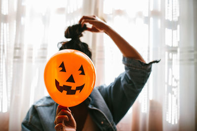 Close-up of woman holding halloween decoration against face at home