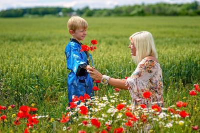 Mother with son by red flowers on land