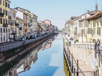 Reflection of buildings in canal against clear sky