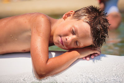 Handsome teenage boy having fun floating on a swim board