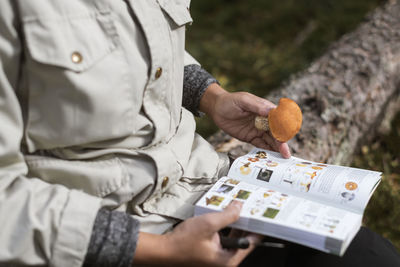 Woman checking mushroom in book